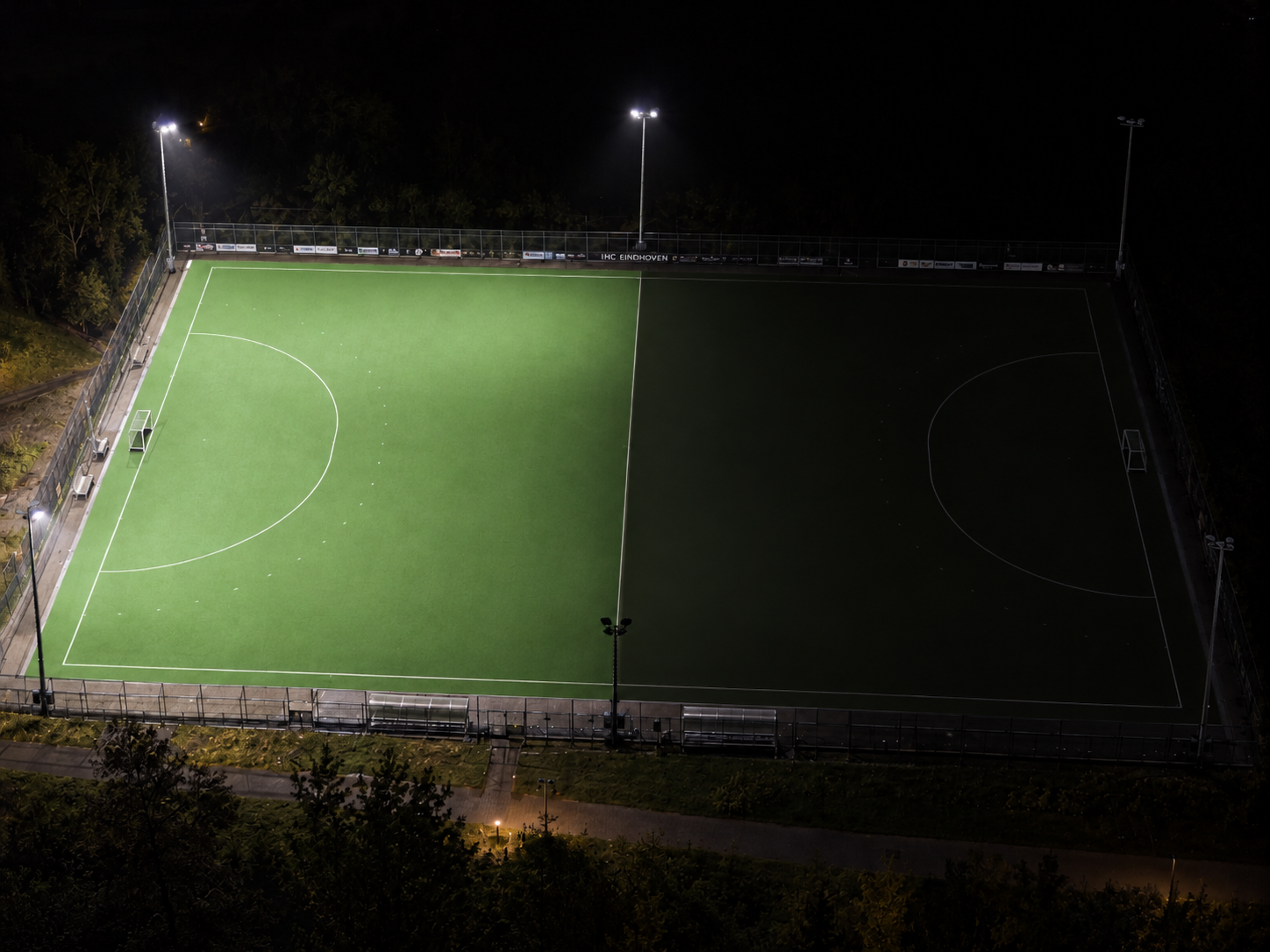 Aerial view of a hockey pitch at night, with one half illuminated
